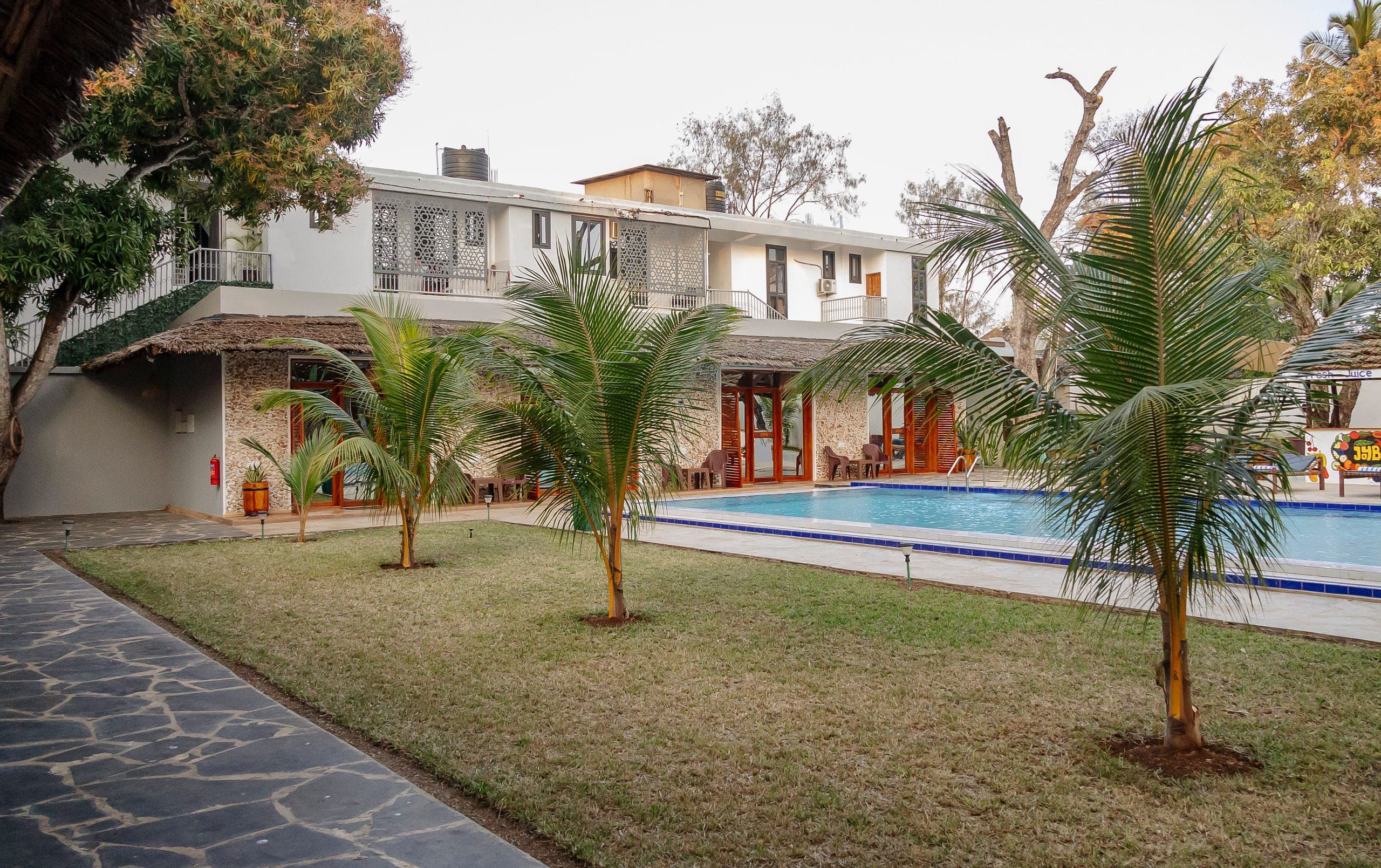 The lawn at JoyB Resort beneath old mango trees and young palms
